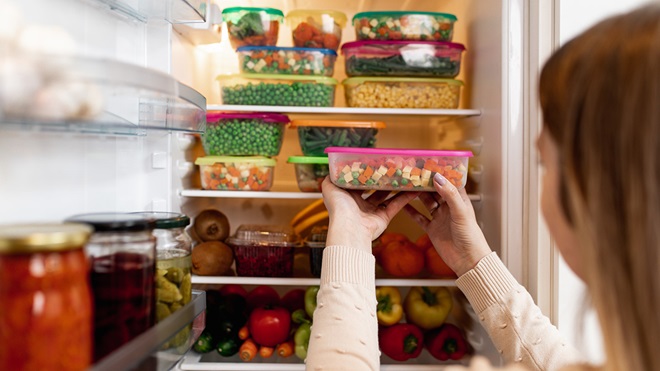 woman putting plastic food containers in fridge